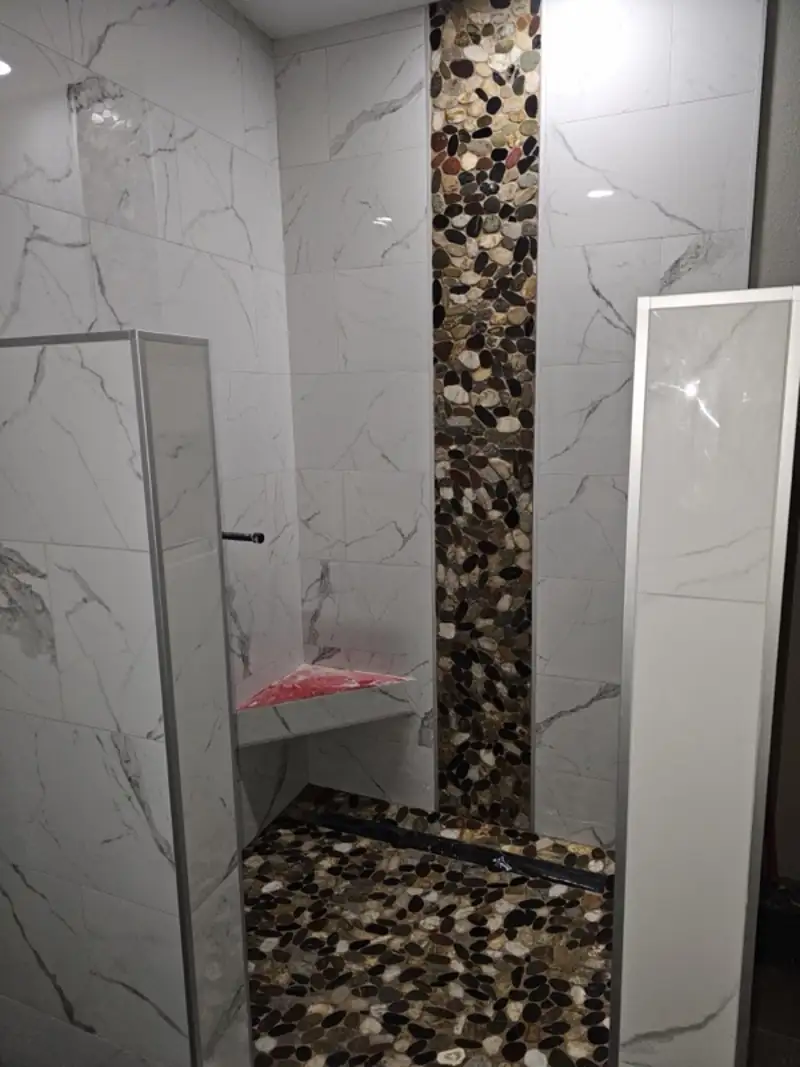 Marble shower with a river rock inlay and built-in bench