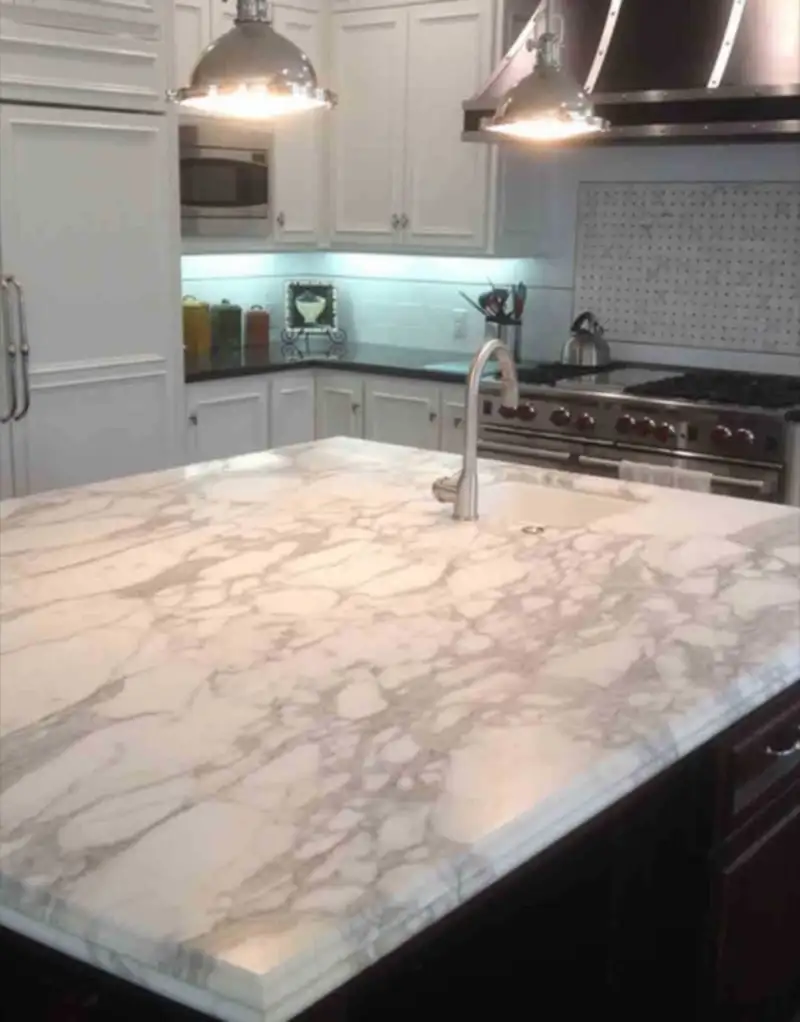 Kitchen with a marble island, stainless range and vent hood