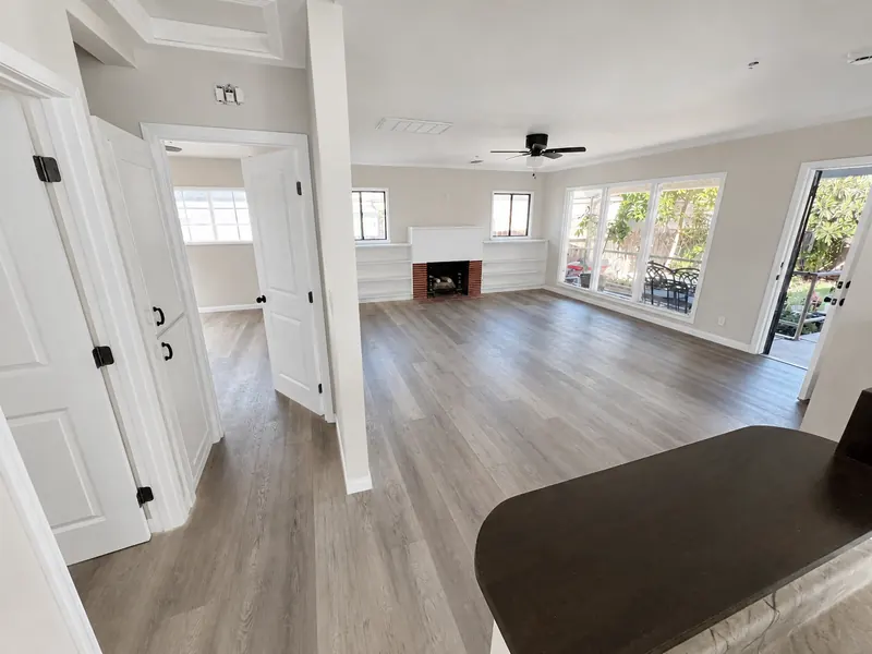 Open living room with a white brick fireplace, built-in shelving and wood-look floor